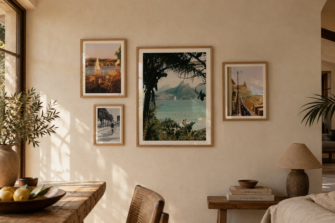 Travel gallery wall of four analog film photography prints in oak frames: Ipanema, Aswan, Copacabana and Lisbon in a sunlit Mediterranean room