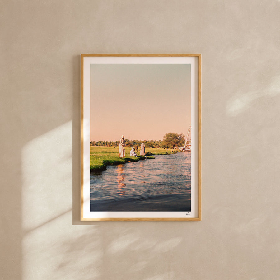 Fishermen on a grassy bank of the Nile at golden hour, Egypt — analog film photography print framed in natural oak