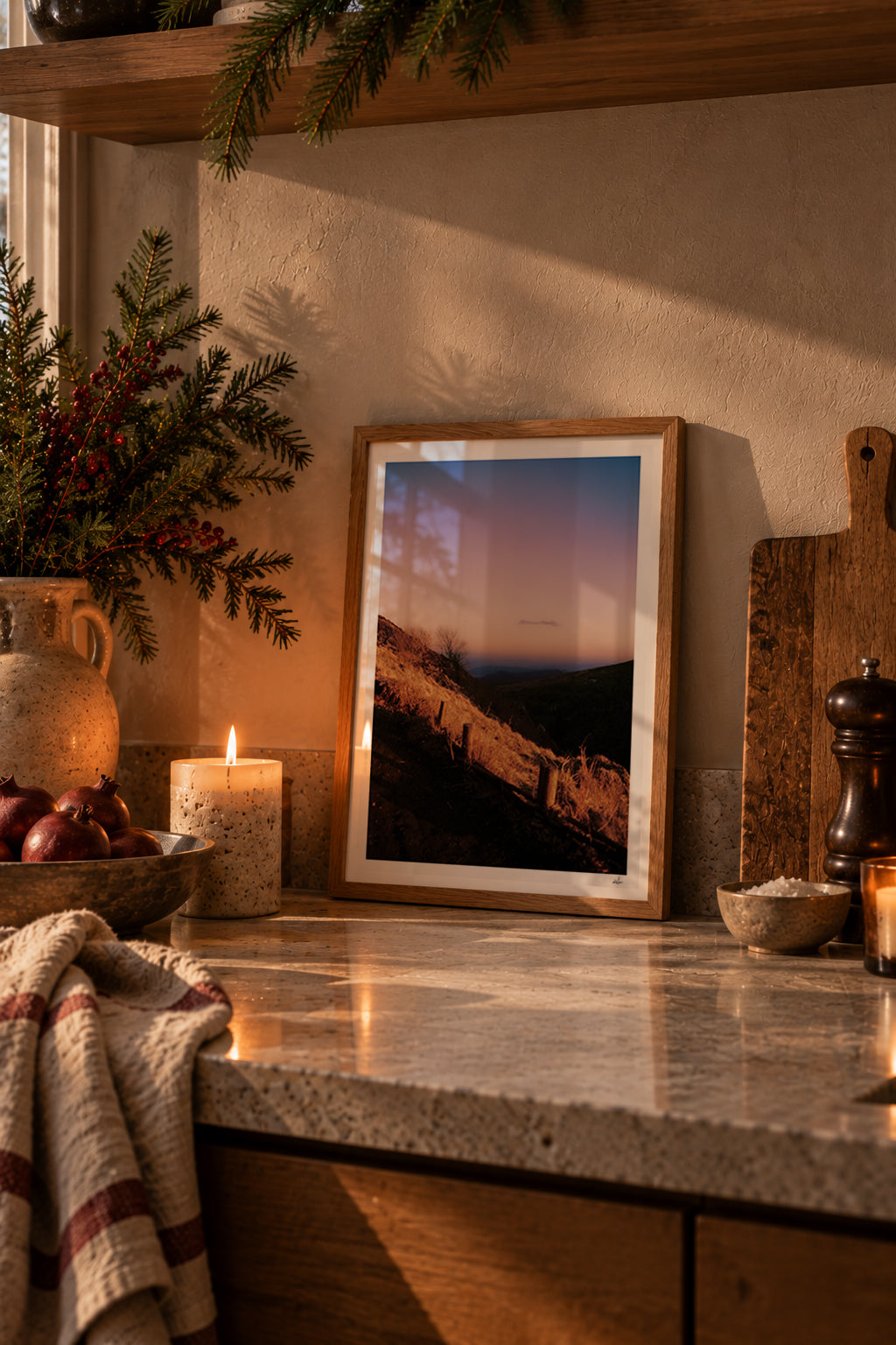 Winter dusk over the Chaîne des Puys, Auvergne, France — framed print leaning on a stone kitchen counter beside a candle