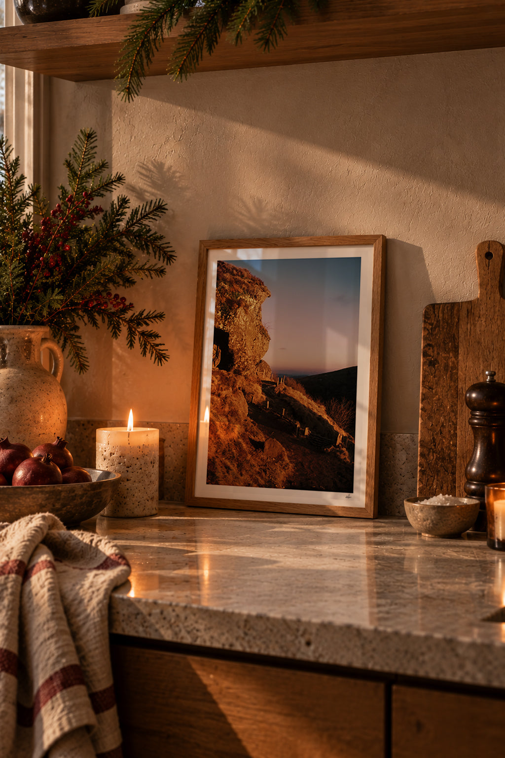 Golden winter light on a volcanic rock at the Puy de Clierzou, Auvergne, France — framed print leaning on a stone kitchen counter beside a candle