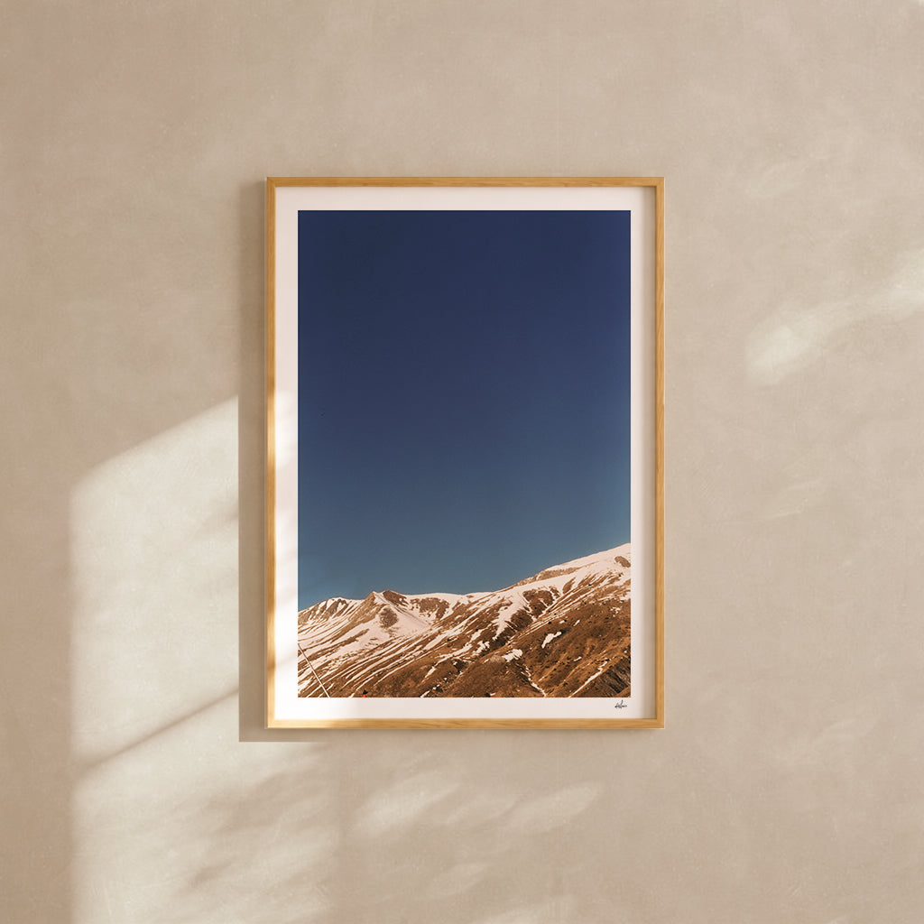 Snow-streaked ridges under a deep blue sky, French Alps, France — analog film photography print framed in natural oak
