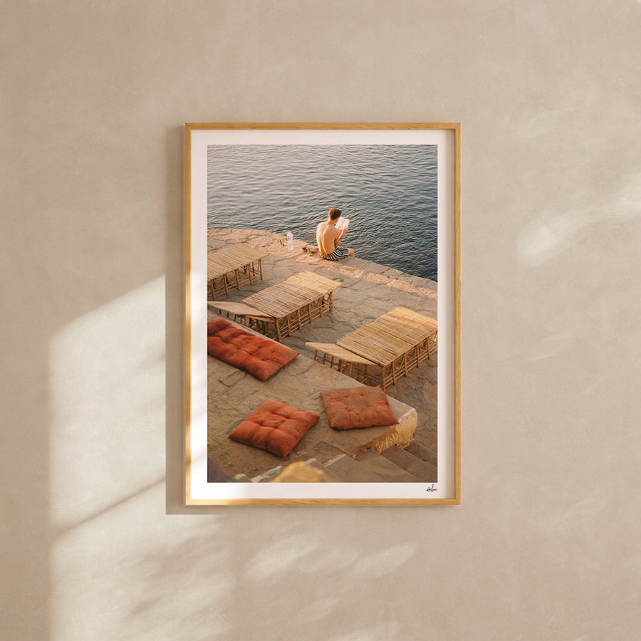 Man reading on a Nile terrace with terracotta cushions, Aswan, Egypt — analog film photography print framed in natural oak